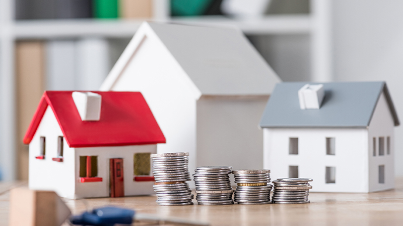 3 house models and some coins on the table with a key