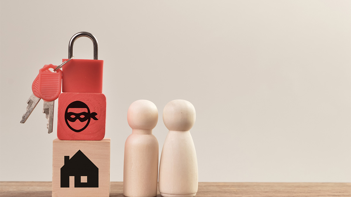 Wooden doll and house figures with padlock showing buying house scams.