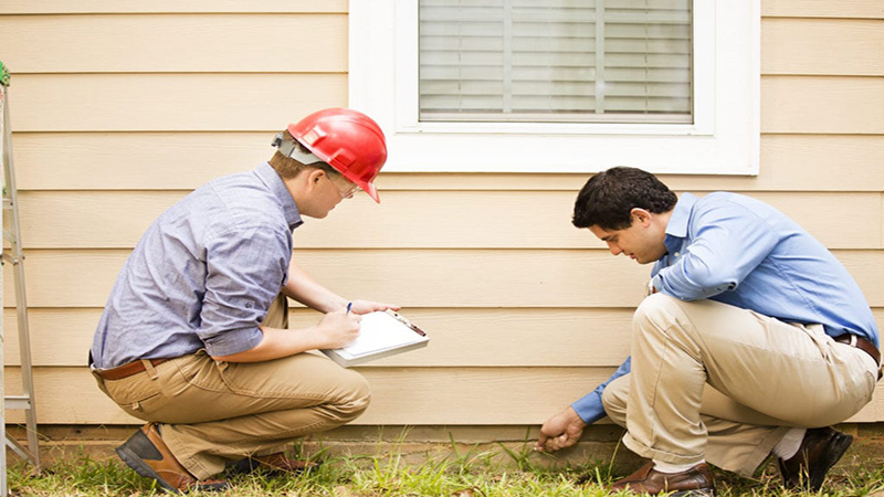 Image of 2 person inspecting outside of house