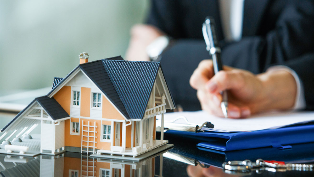 Image of person signing paper and a miniature house