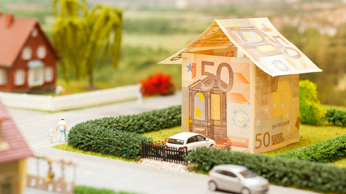 A money house model with miniature cars in a village scenery.
