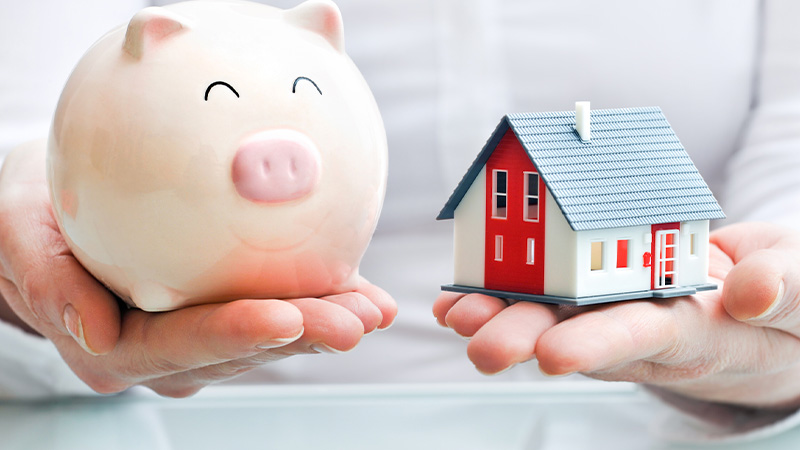 A person with a piggy bank and a house on his/her hand