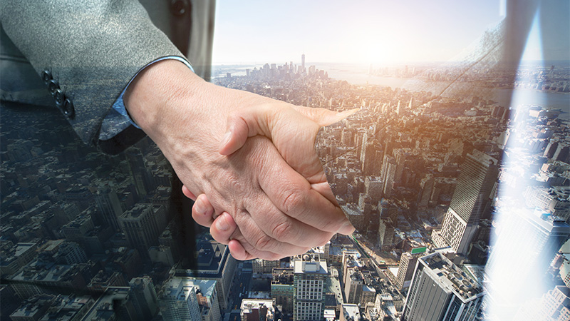 Image of hands shaking with buildings in the background