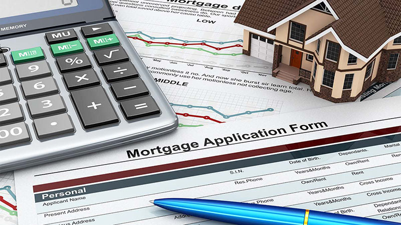 Image of mortgage application with ball pen, calculator, and miniature house