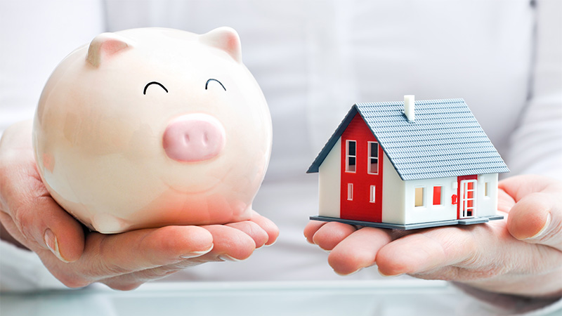 Image of person holding a Piggy bank and small house