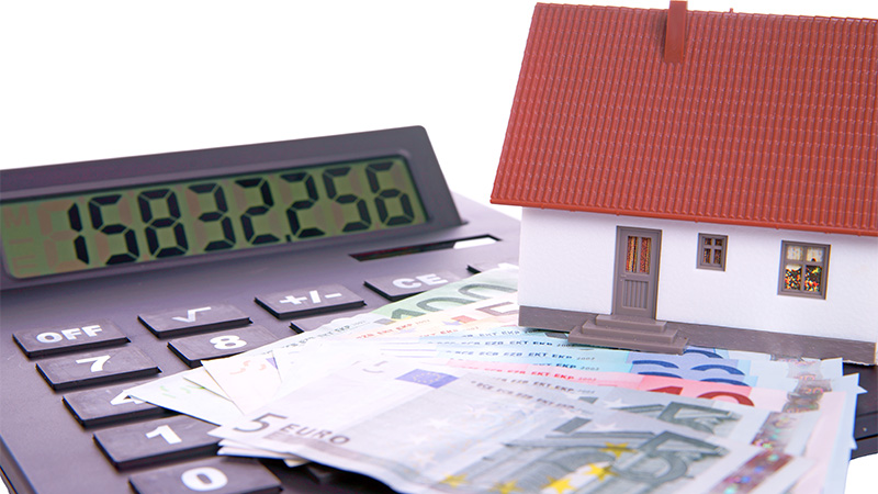 Image of small house and calculator with money on top of it