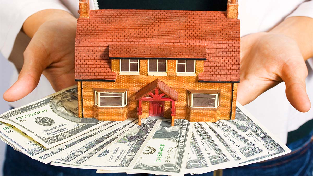 Image of a person holding a miniature house and money